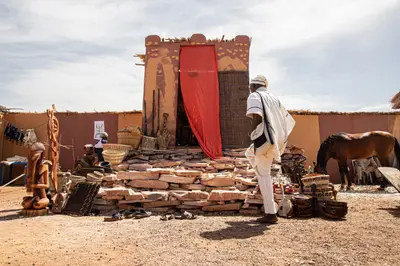 Facade de banco et tenture rouge, un visiteur en boubou blanc