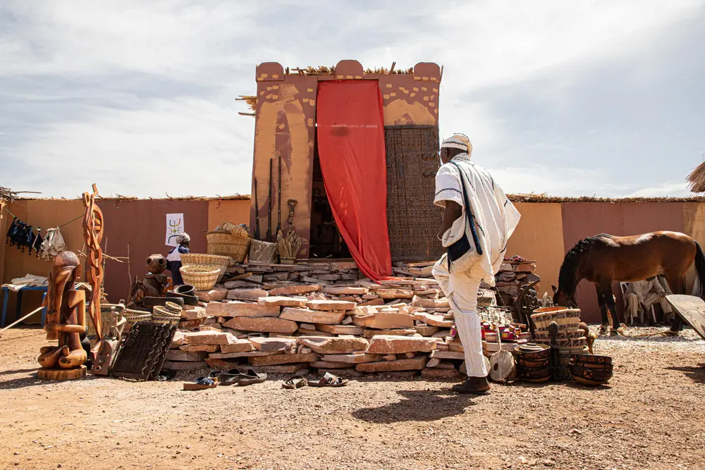 Facade de banco et tenture rouge, un visiteur en boubou blanc
